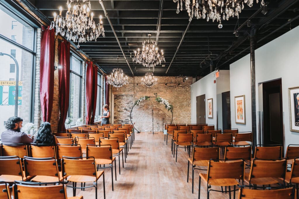 Ceremony space at Watson Block in Minneapolis set up with a floral arch, exposed brick, and crystal chandeliers before guests arrive — wedding venue photography by Eric Turner Photography